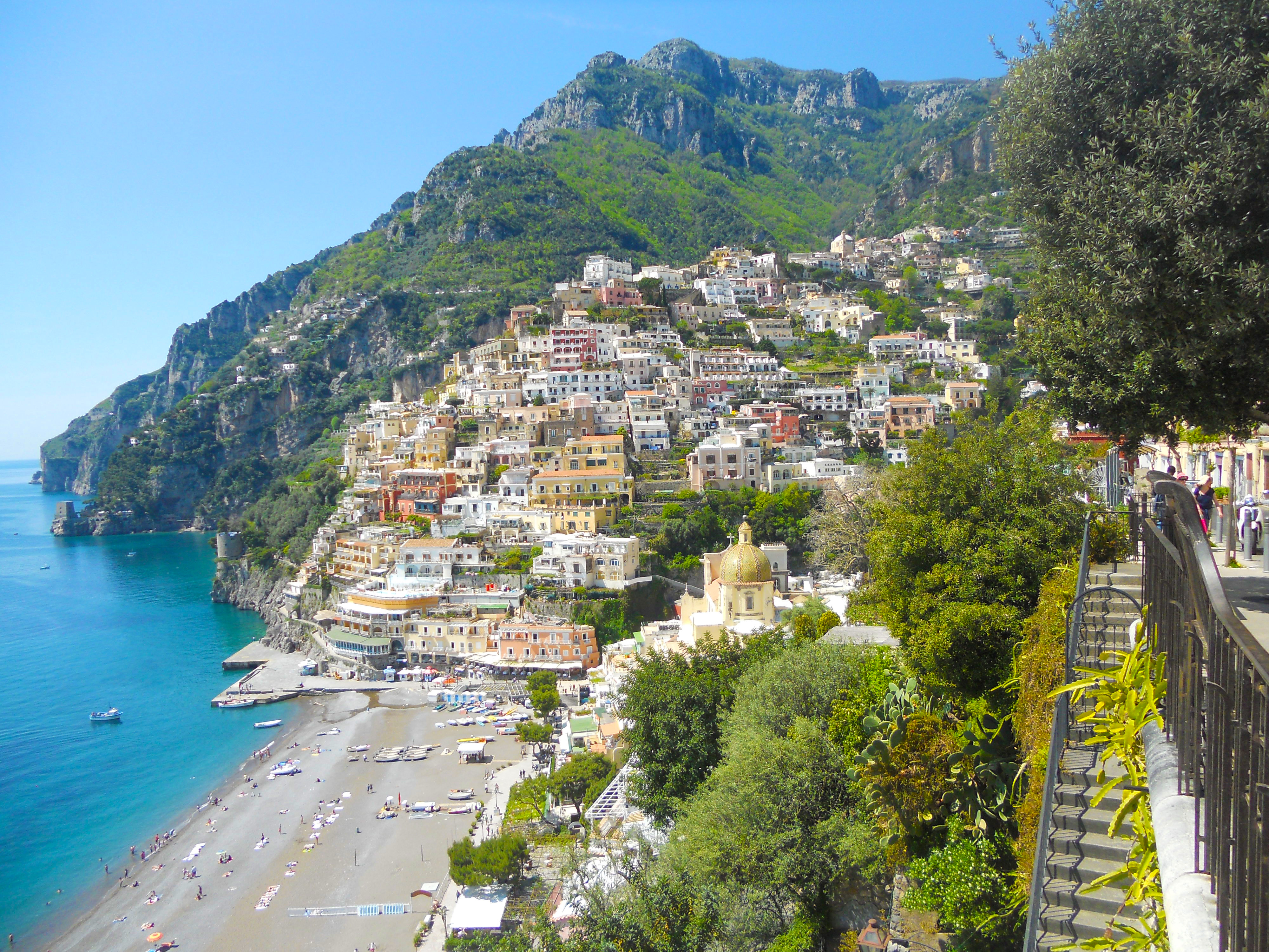 Wide view of Positano with beach, colorful buildings, and surrounding mountains