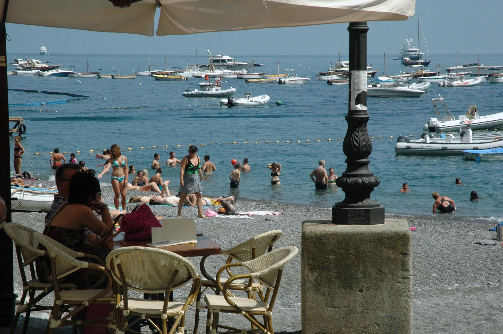 People on the beach with boats anchored in the bay near Positano