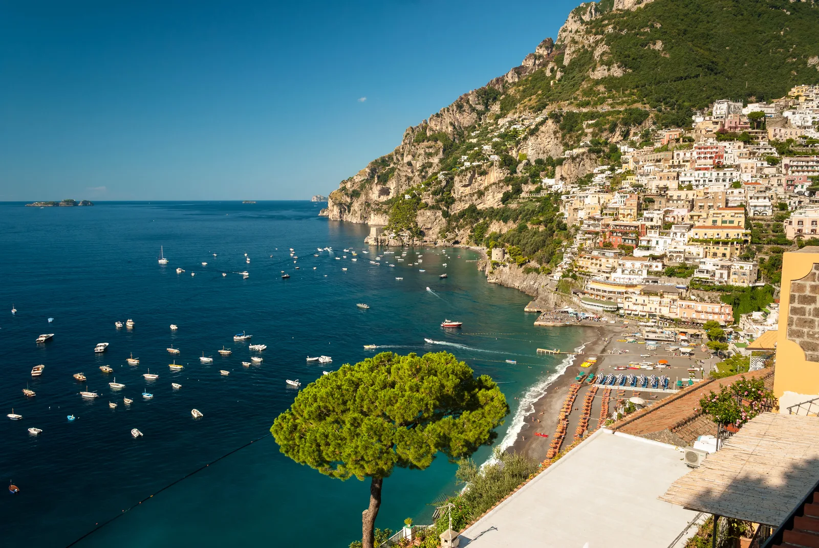 Wide view of Positano's Spiaggia Grande with colorful umbrellas and the cliffside town behind it
